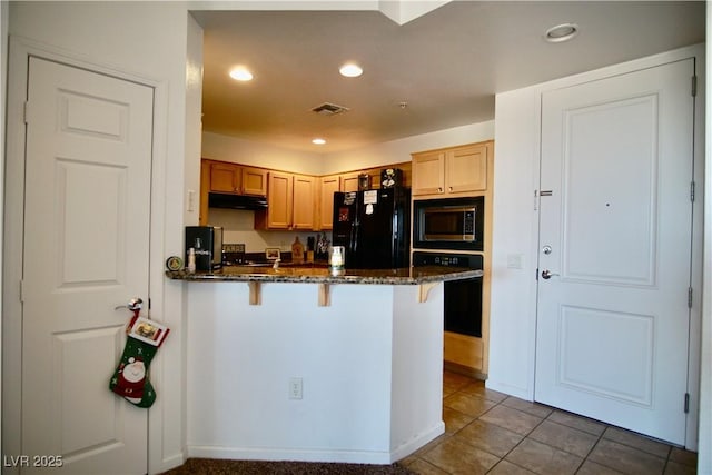 kitchen with a breakfast bar area, black appliances, tile patterned floors, kitchen peninsula, and dark stone counters