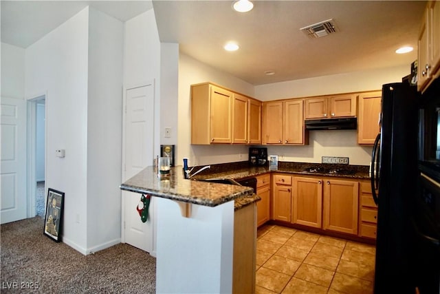 kitchen with a breakfast bar, sink, kitchen peninsula, dark stone counters, and black appliances