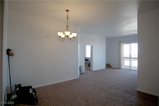 carpeted spare room featuring a chandelier