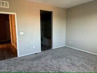 unfurnished bedroom featuring a walk in closet and dark colored carpet