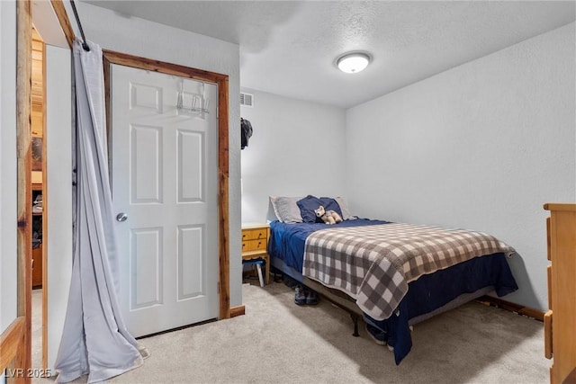 bedroom with a textured ceiling and light carpet