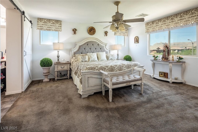 bedroom featuring ceiling fan, dark carpet, multiple windows, and a barn door