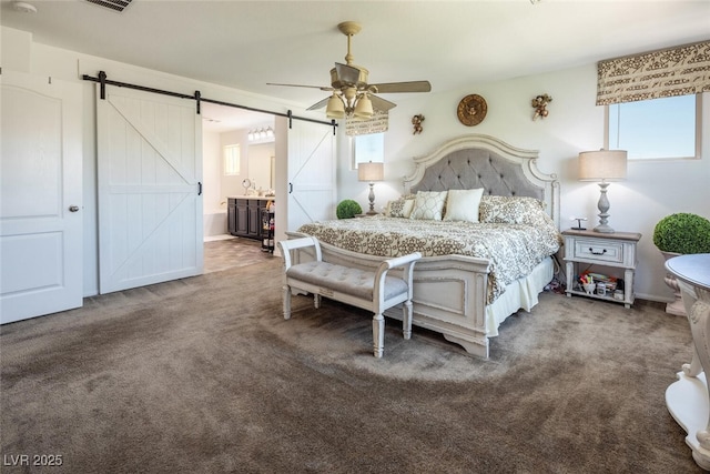 carpeted bedroom with ceiling fan, ensuite bath, and a barn door