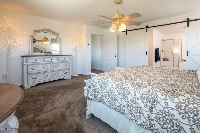 bedroom with ceiling fan, a barn door, ensuite bathroom, and dark carpet