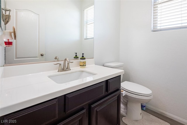 bathroom featuring toilet, vanity, and hardwood / wood-style flooring