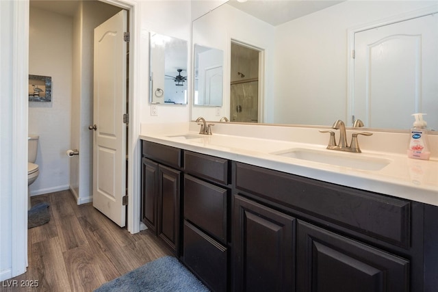 bathroom with hardwood / wood-style floors, vanity, a shower with door, toilet, and ceiling fan