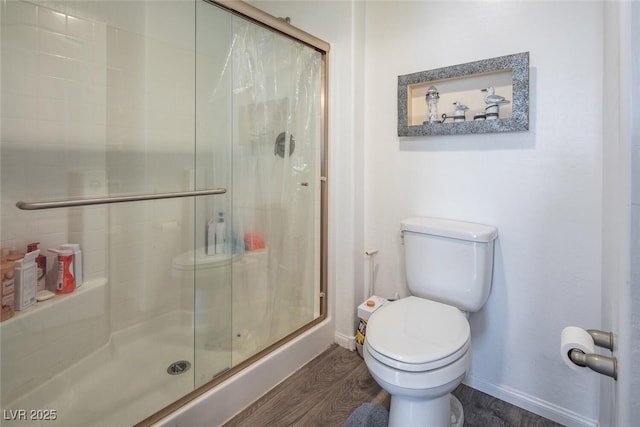 bathroom with hardwood / wood-style flooring, toilet, and a shower with door