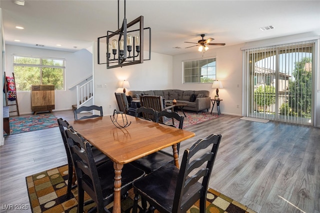 dining area featuring wood-type flooring and ceiling fan with notable chandelier