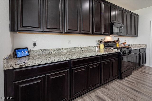 kitchen featuring black appliances, light stone countertops, and light hardwood / wood-style flooring