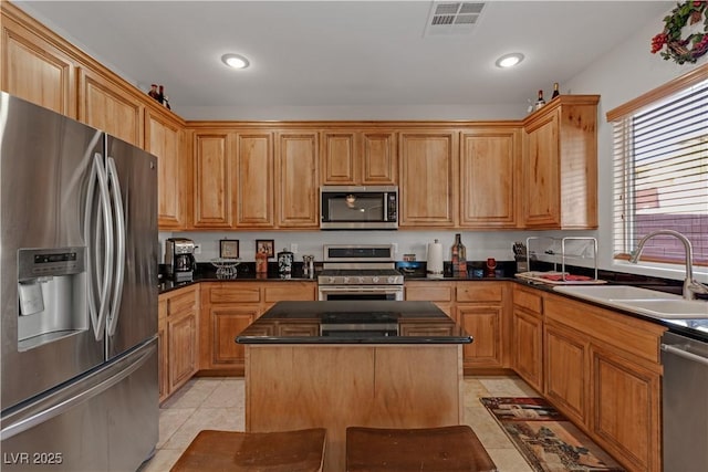 kitchen with a kitchen island, light tile patterned flooring, appliances with stainless steel finishes, and sink