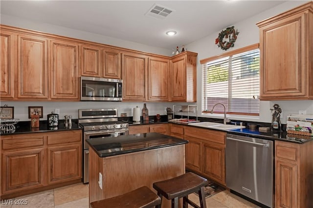 kitchen with sink, light tile patterned floors, a center island, and stainless steel appliances