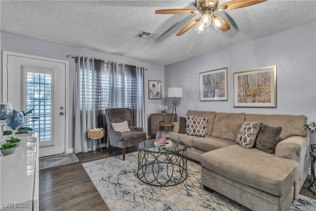 living room featuring ceiling fan, dark wood-type flooring, and a textured ceiling