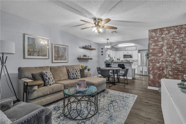 living room featuring ceiling fan, dark hardwood / wood-style flooring, and a textured ceiling