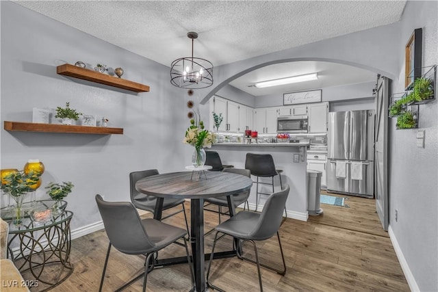 dining area with light hardwood / wood-style floors and a textured ceiling