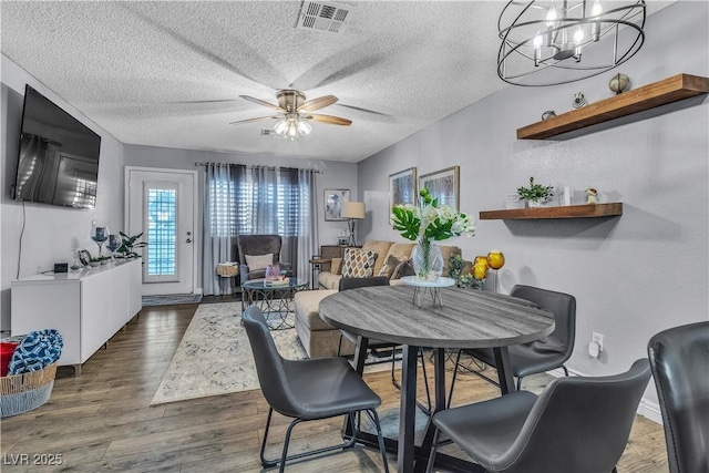 dining space featuring ceiling fan, a textured ceiling, and dark hardwood / wood-style flooring