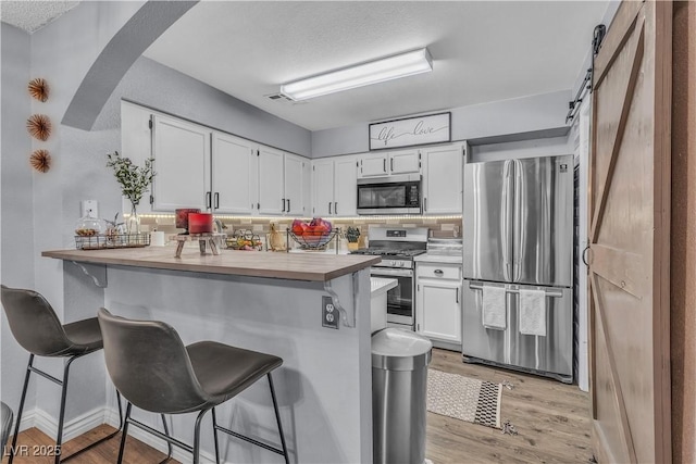 kitchen with white cabinets, stainless steel appliances, kitchen peninsula, and a breakfast bar area