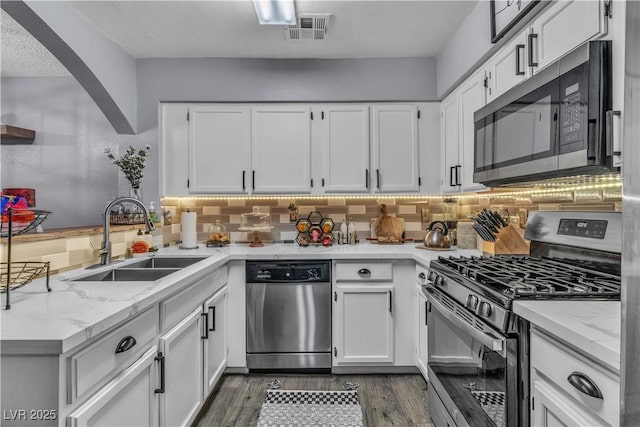 kitchen featuring sink, stainless steel appliances, white cabinetry, and light stone countertops