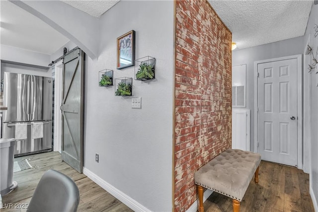 entrance foyer with a textured ceiling, light hardwood / wood-style flooring, brick wall, and a barn door