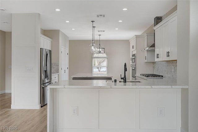 kitchen featuring decorative light fixtures, kitchen peninsula, sink, stainless steel appliances, and white cabinets