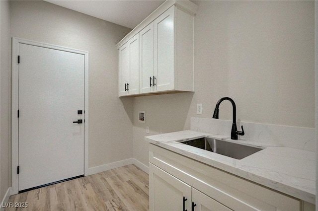 laundry area featuring washer hookup, cabinets, light hardwood / wood-style flooring, and sink