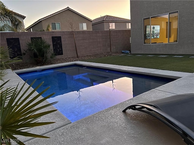 pool at dusk featuring a yard