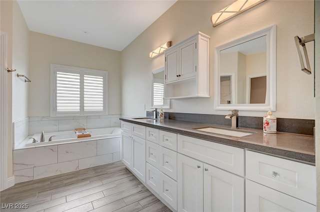 bathroom with vanity, a relaxing tiled tub, and hardwood / wood-style floors