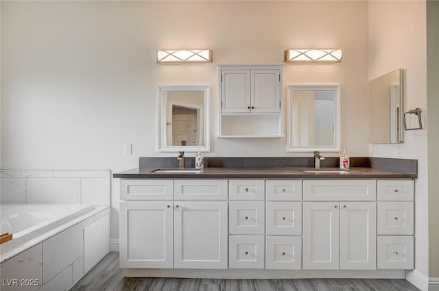 bathroom featuring tiled bath, vanity, and hardwood / wood-style flooring