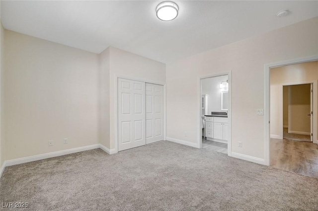 unfurnished bedroom with ensuite bathroom, a closet, and light carpet