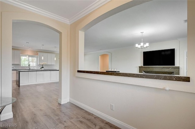 hall with ornamental molding, light hardwood / wood-style floors, and sink