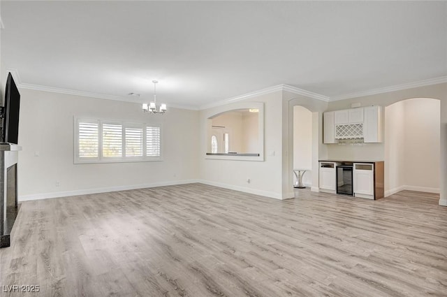 unfurnished living room with wine cooler, crown molding, and light hardwood / wood-style flooring