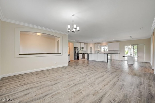 unfurnished living room with crown molding, light hardwood / wood-style floors, and a notable chandelier