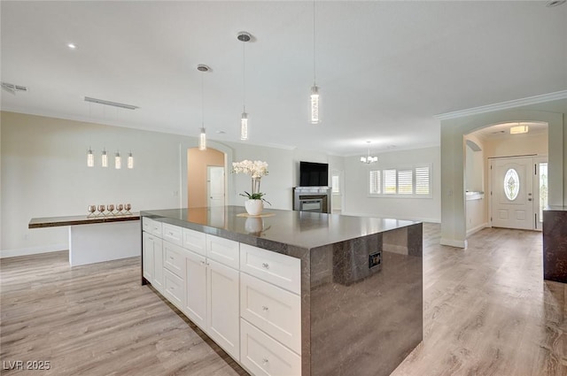 kitchen featuring pendant lighting, a kitchen island, white cabinetry, light hardwood / wood-style flooring, and crown molding