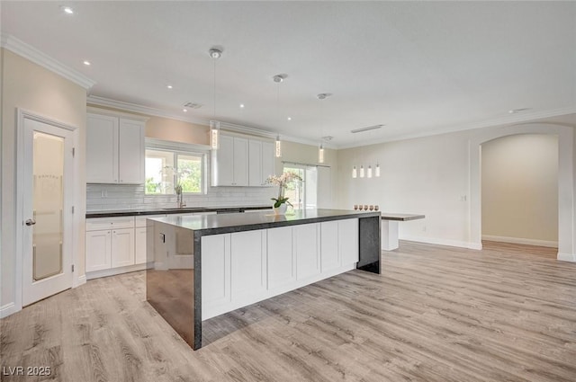 kitchen featuring decorative light fixtures, white cabinets, tasteful backsplash, and a kitchen island