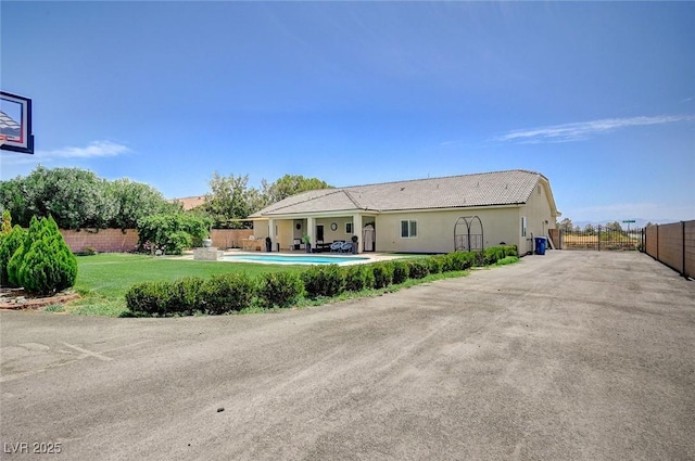 rear view of property featuring a fenced in pool and a yard