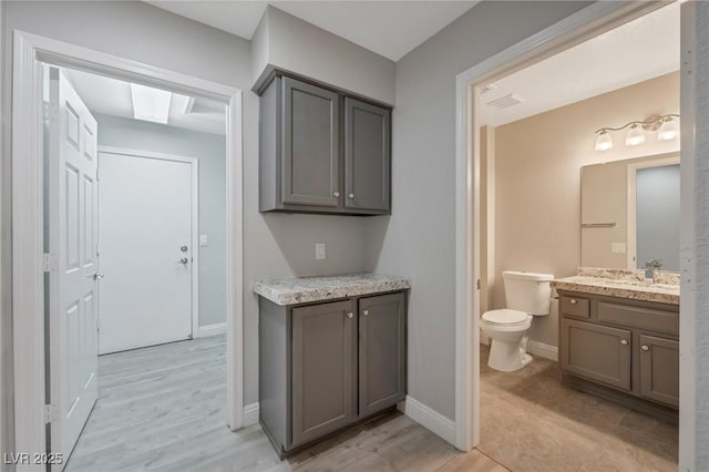 bathroom with toilet, vanity, and wood-type flooring