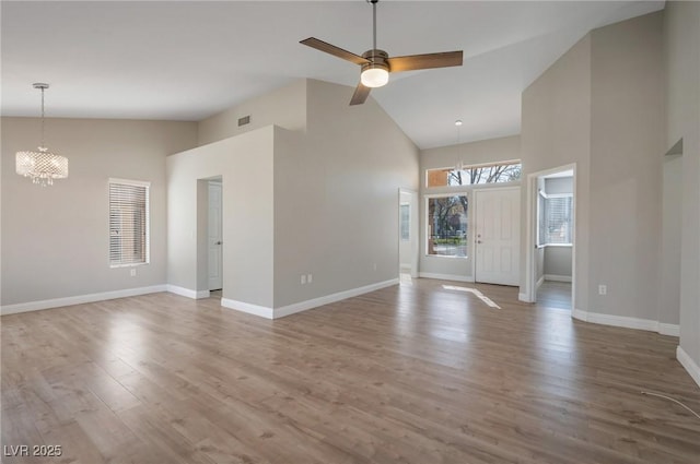 unfurnished living room featuring high vaulted ceiling, hardwood / wood-style flooring, and ceiling fan with notable chandelier