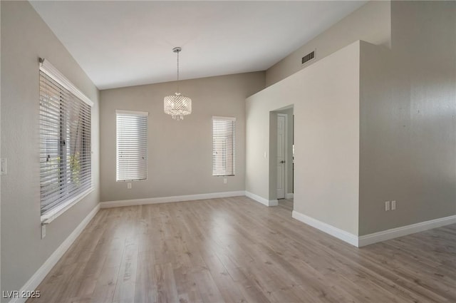 unfurnished room featuring light wood-type flooring, vaulted ceiling, and a chandelier