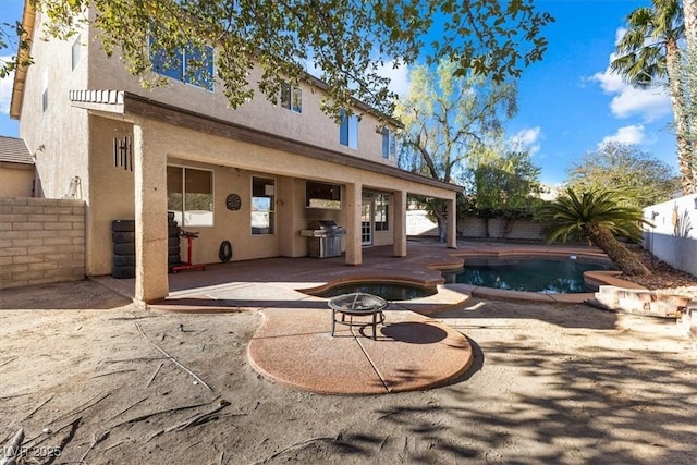 back of house with a patio area, an outdoor fire pit, and a fenced in pool