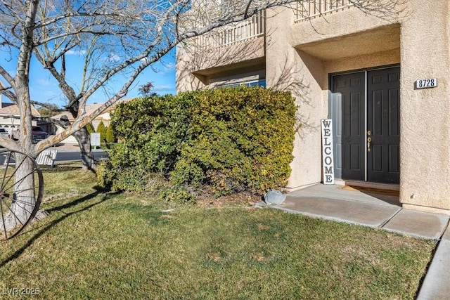 entrance to property featuring a balcony and a yard