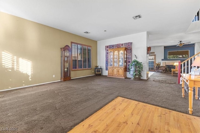 unfurnished living room featuring carpet, a tiled fireplace, and ceiling fan