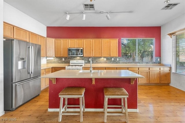 kitchen featuring a breakfast bar area, sink, stainless steel appliances, and a center island with sink