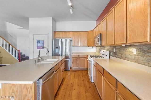 kitchen featuring tasteful backsplash, light hardwood / wood-style floors, a center island with sink, sink, and appliances with stainless steel finishes