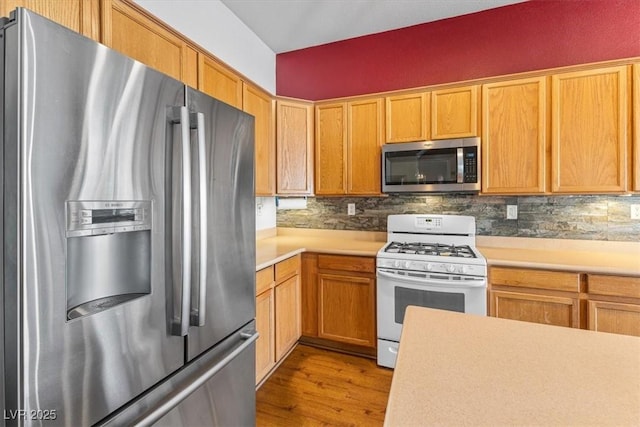 kitchen featuring light wood-type flooring, backsplash, and stainless steel appliances