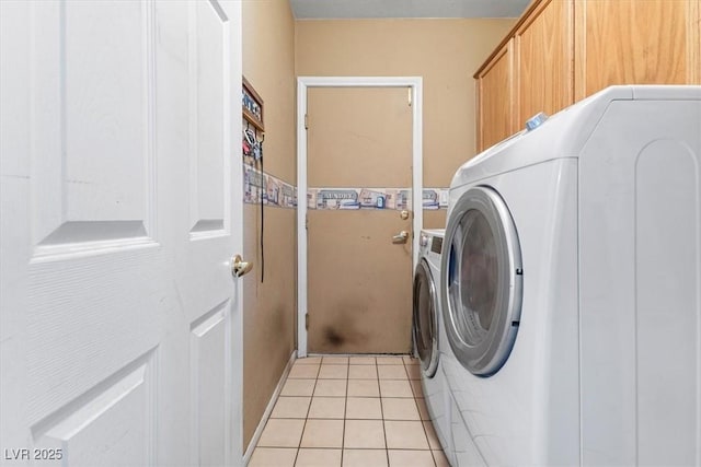 clothes washing area featuring washer and dryer, cabinets, and light tile patterned flooring