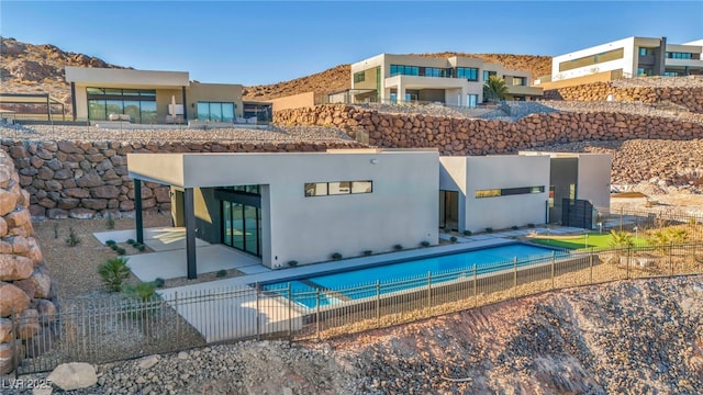 back of property featuring a fenced in pool and a patio