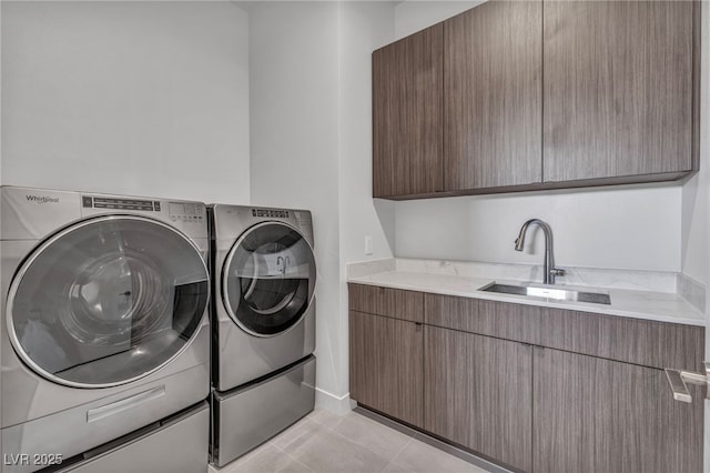 laundry room with sink, light tile patterned floors, washer and clothes dryer, and cabinets