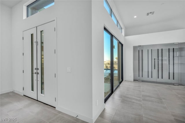 tiled entryway with a towering ceiling and french doors