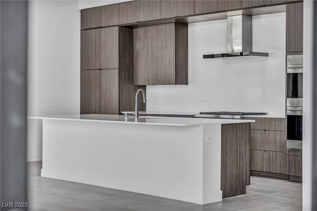 kitchen with wall chimney exhaust hood, stainless steel gas stovetop, and sink