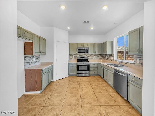 kitchen with sink, stainless steel appliances, green cabinets, and light tile patterned flooring