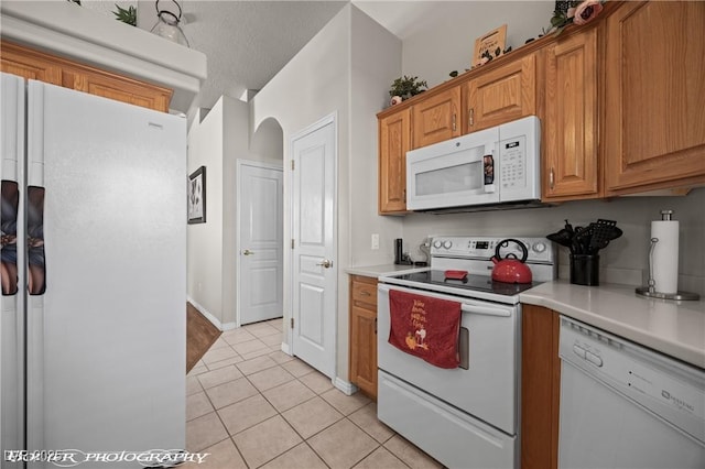 kitchen with light tile patterned flooring, white appliances, and a textured ceiling